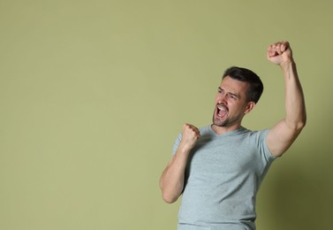 Photo of Portrait of happy winner on pale olive background, space for text