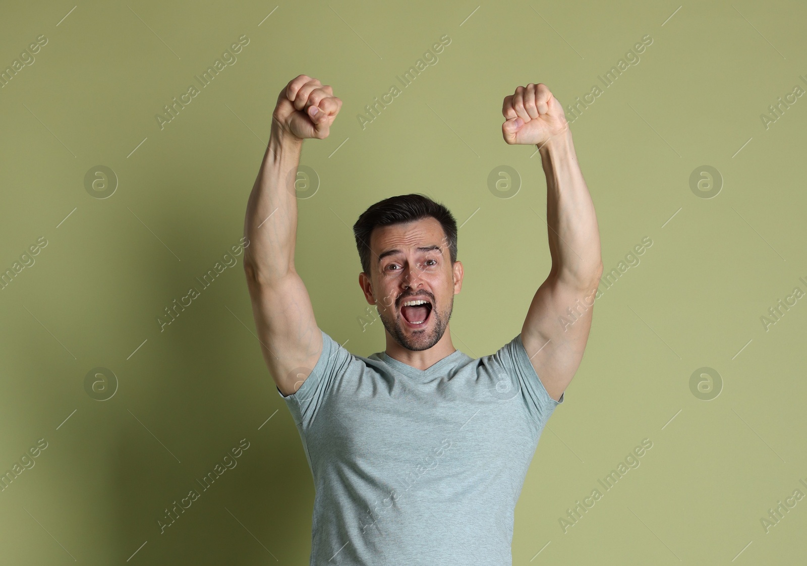 Photo of Portrait of happy winner on pale olive background