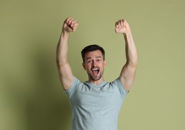 Portrait of happy winner on pale olive background