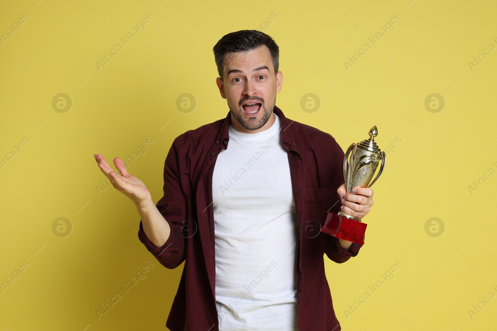 Photo of Happy winner with golden trophy cup on yellow background