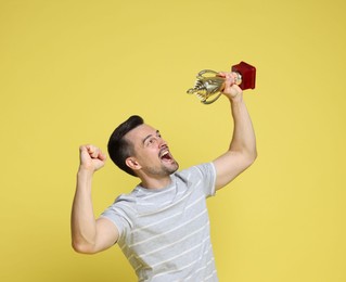 Happy winner with golden trophy cup on yellow background