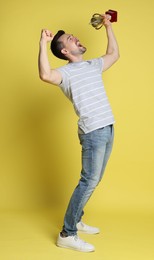 Happy winner with golden trophy cup on yellow background