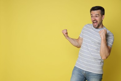 Portrait of happy winner on yellow background, space for text