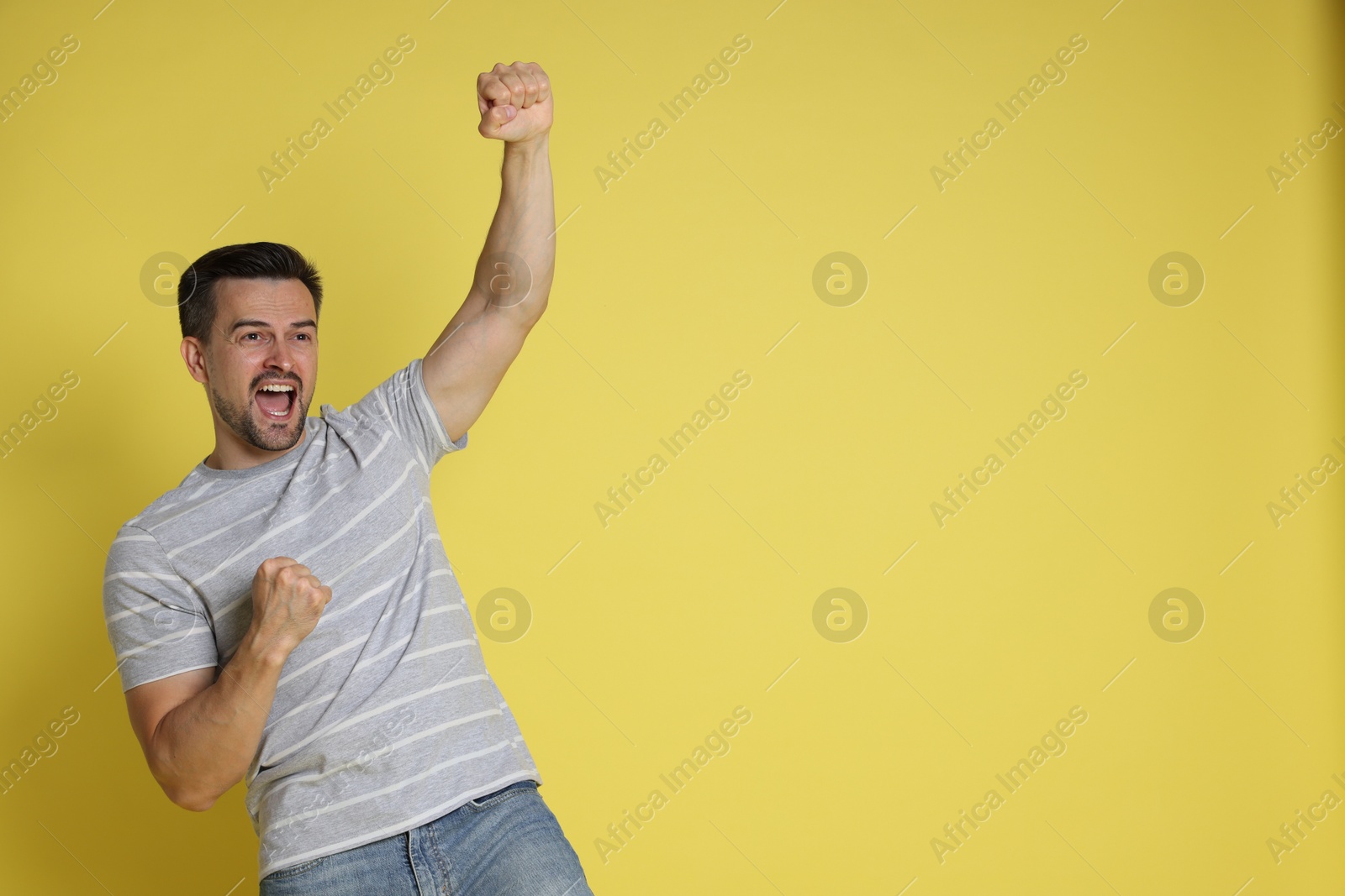 Photo of Portrait of happy winner on yellow background, space for text