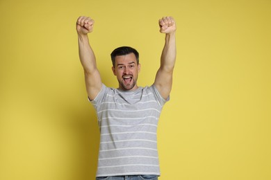 Portrait of happy winner on yellow background