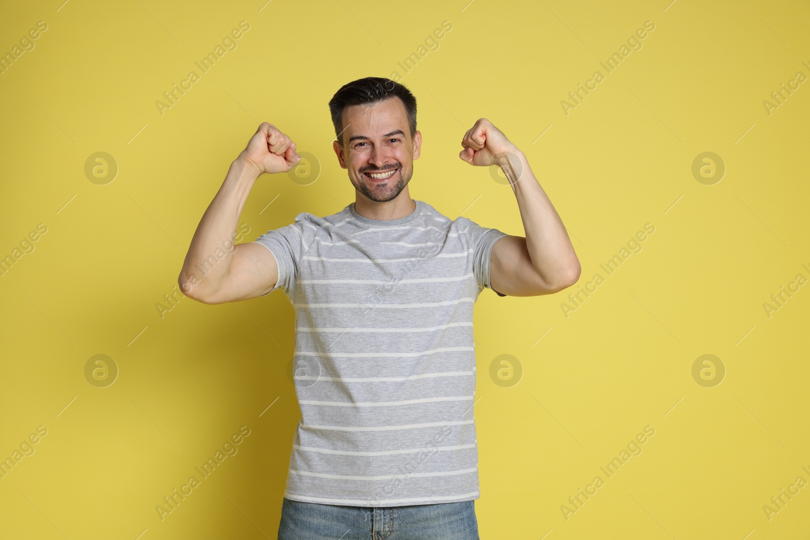 Photo of Portrait of happy winner on yellow background