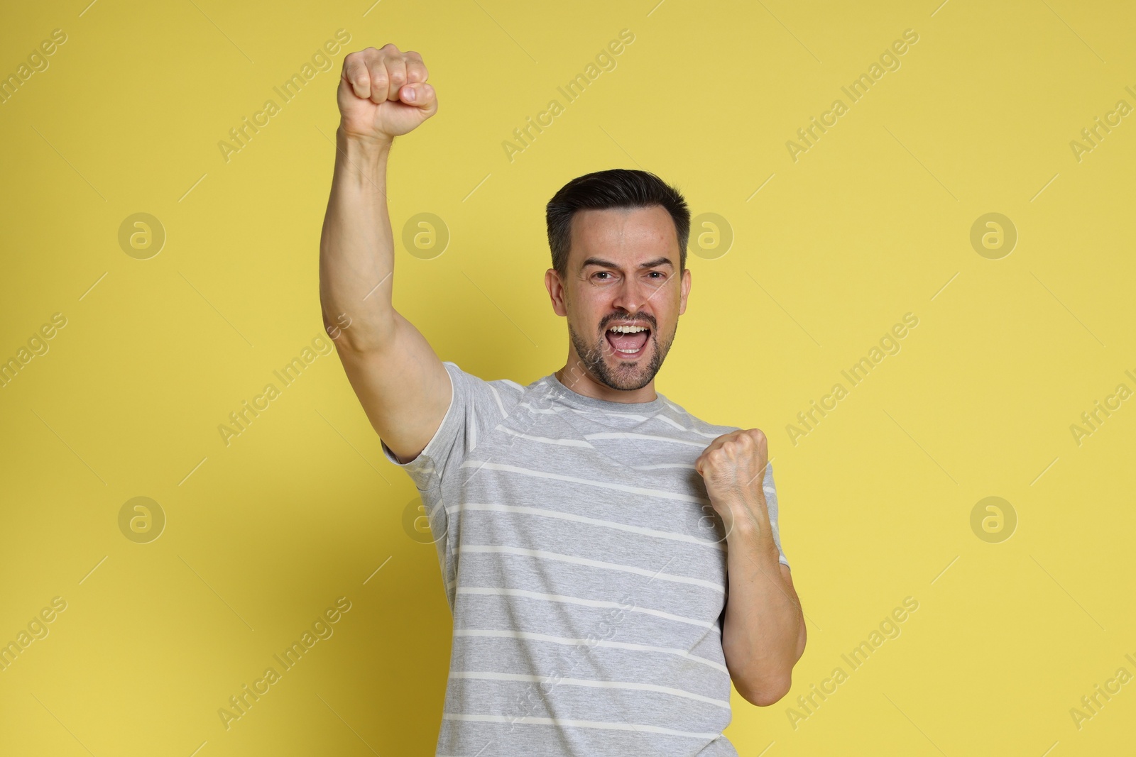 Photo of Portrait of happy winner on yellow background