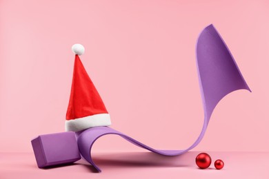 Photo of Yoga mat, block, Santa hat and baubles on pink background