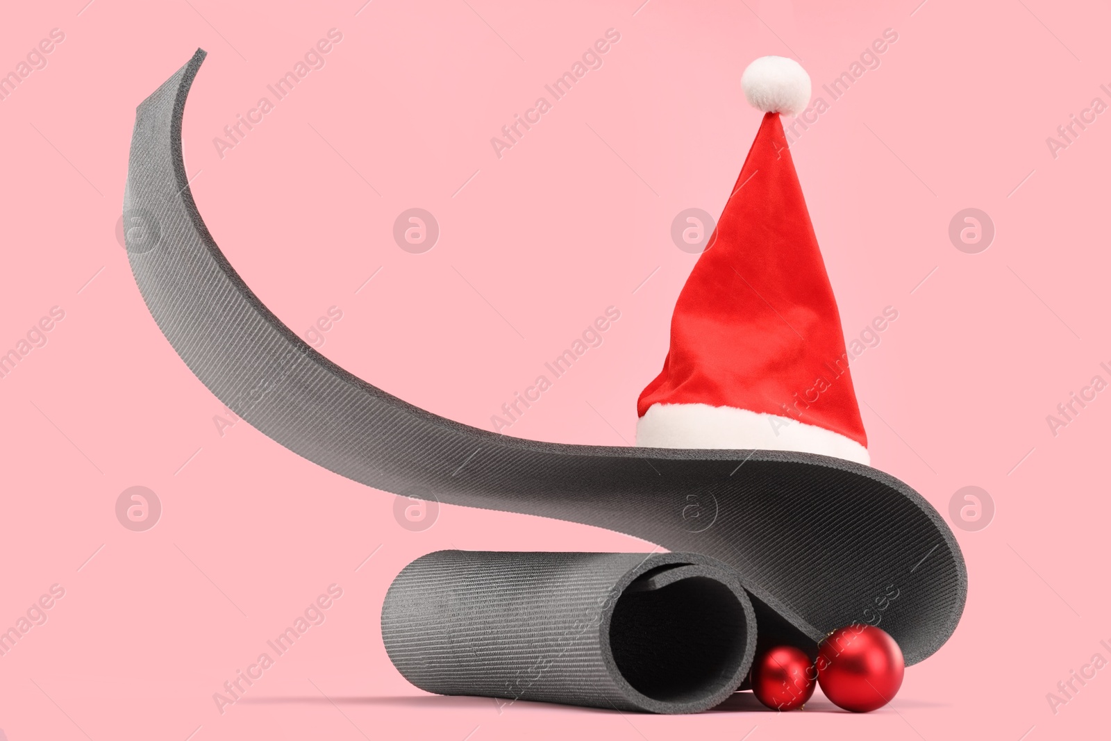 Photo of Yoga mat, Santa hat and baubles on pink background