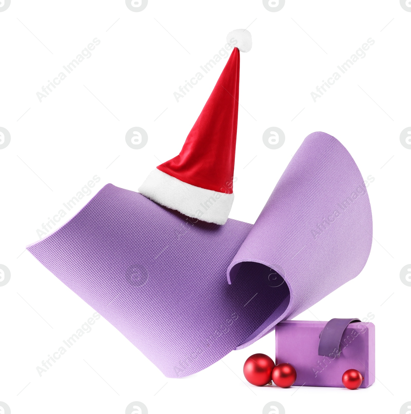 Photo of Yoga mat, block, Santa hat and baubles isolated on white