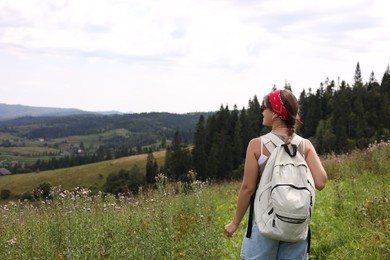 Tourist with backpack enjoying picturesque landscape, back view. Space for text