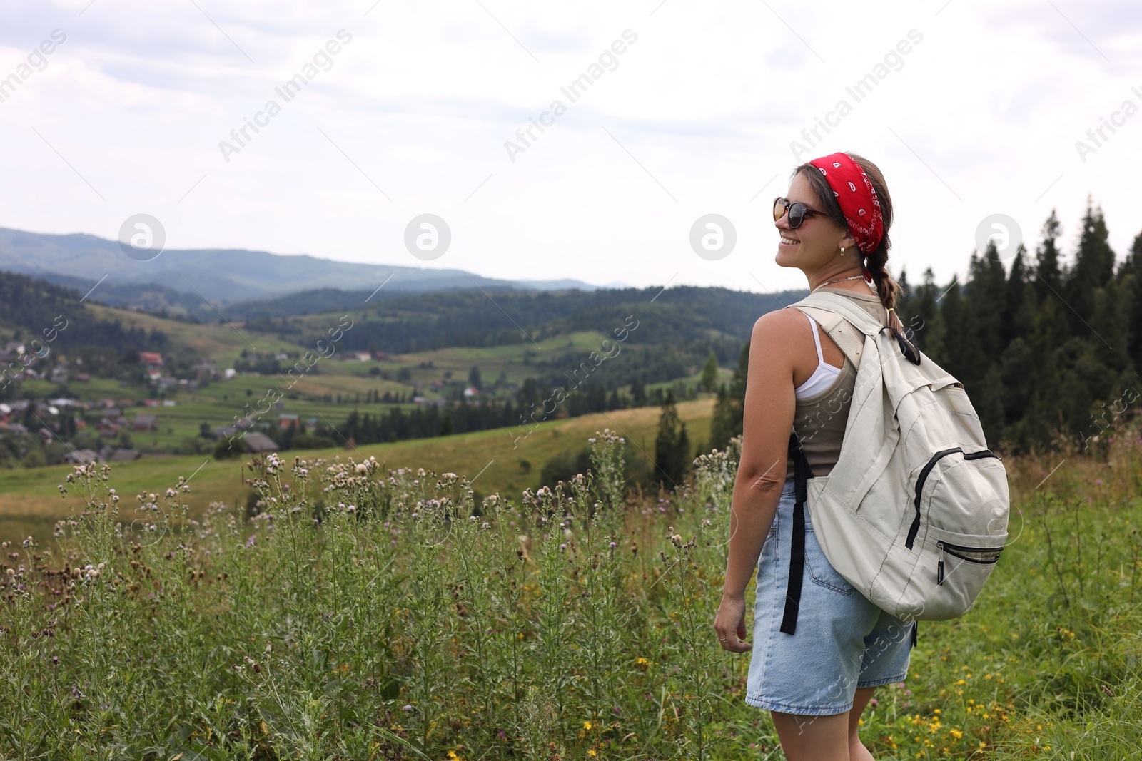 Photo of Smiling tourist with backpack enjoying picturesque landscape. Space for text