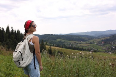 Photo of Smiling tourist with backpack enjoying picturesque landscape. Space for text