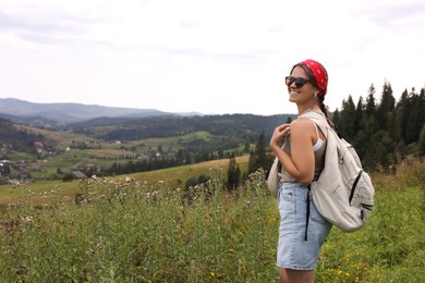 Smiling tourist with backpack enjoying picturesque landscape. Space for text