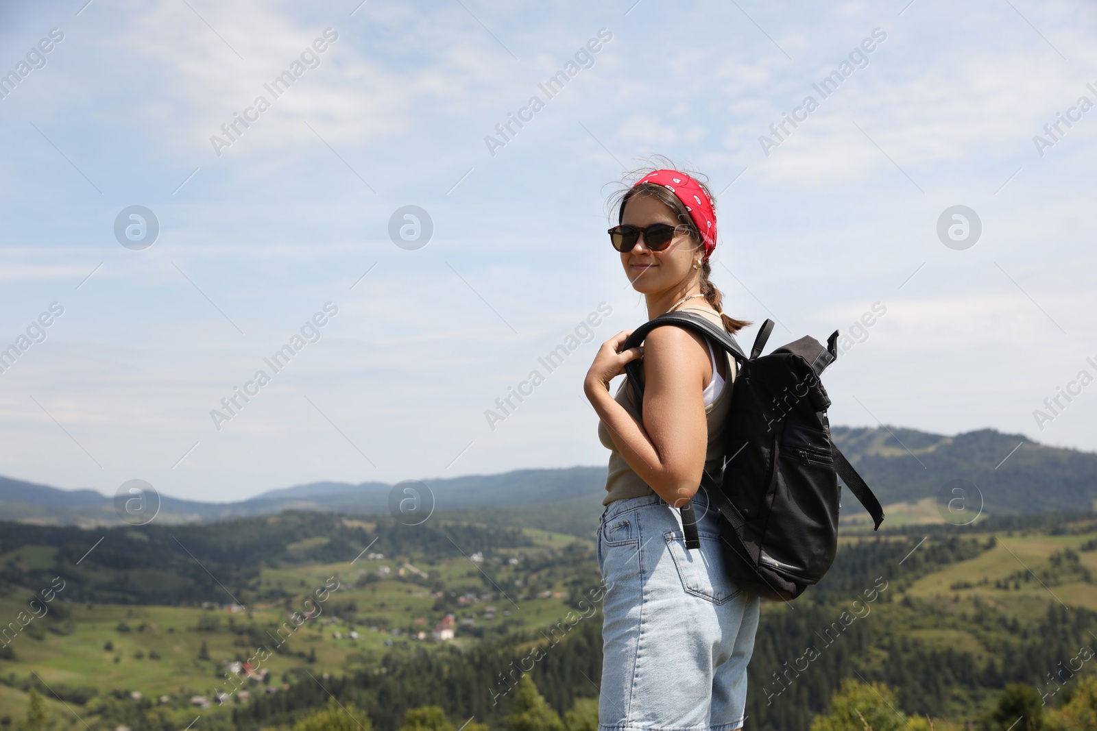 Photo of Smiling tourist with backpack in mountains. Space for text