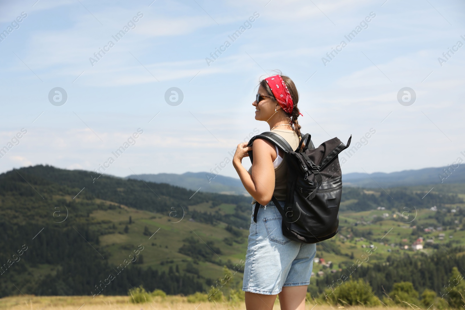 Photo of Smiling tourist with backpack enjoying picturesque landscape. Space for text