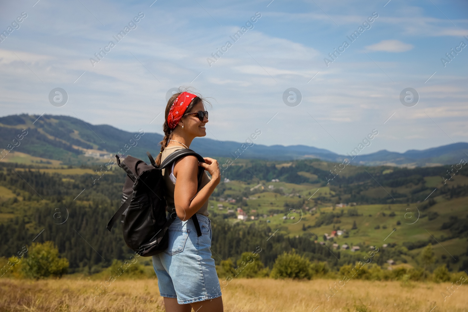 Photo of Smiling tourist with backpack enjoying picturesque landscape. Space for text