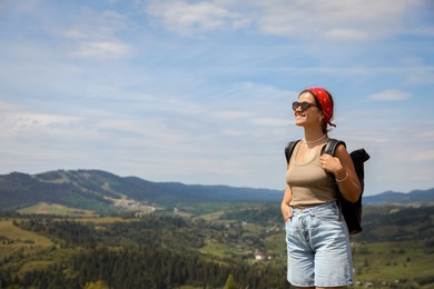 Photo of Smiling tourist with backpack in mountains. Space for text