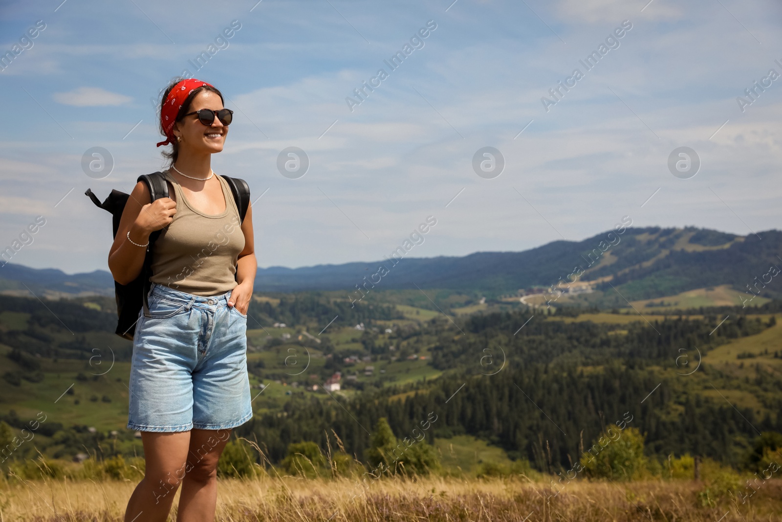 Photo of Smiling tourist with backpack enjoying picturesque landscape. Space for text