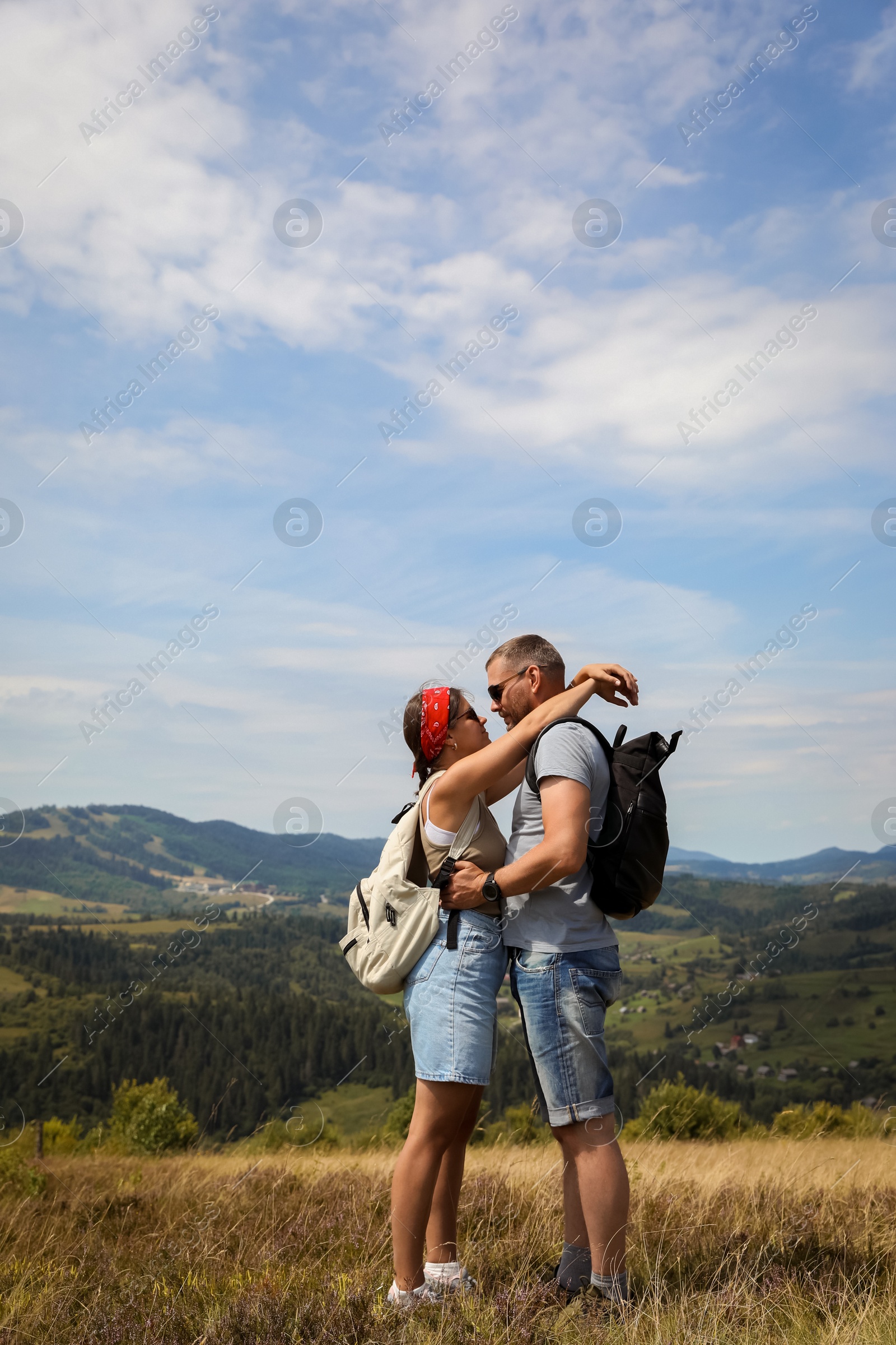 Photo of Couple with backpacks hugging outdoors. Active tourism