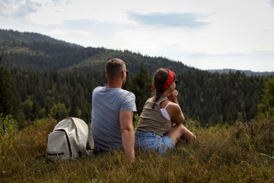 Couple with backpack enjoying picturesque landscape, back view. Active tourism