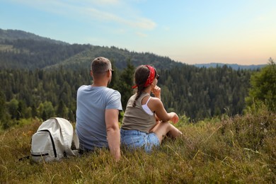 Photo of Couple with backpack enjoying picturesque landscape, back view. Active tourism