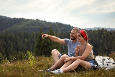 Photo of Couple with backpack looking at something outdoors, space for text. Active tourism