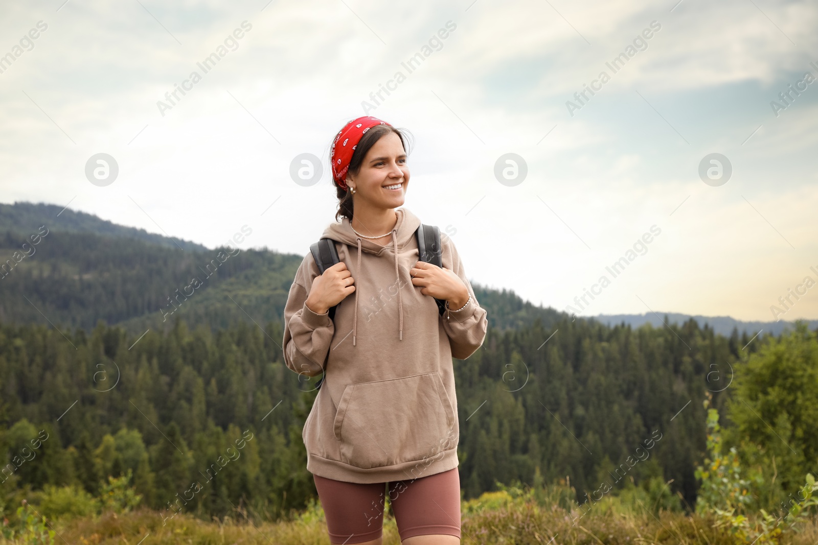 Photo of Smiling tourist with backpack walking in mountains