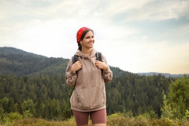 Smiling tourist with backpack walking in mountains