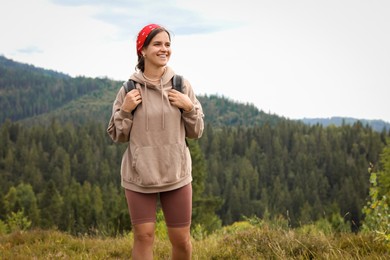 Photo of Smiling tourist with backpack walking in mountains. Space for text