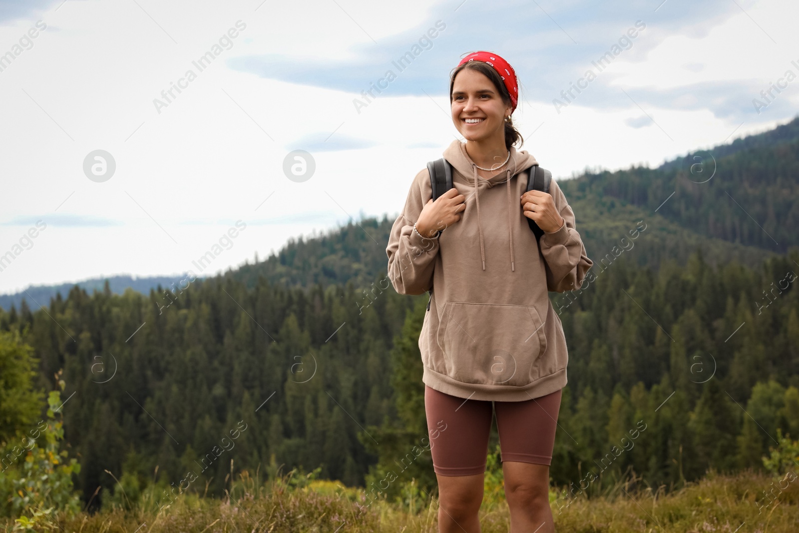 Photo of Smiling tourist with backpack walking in mountains. Space for text