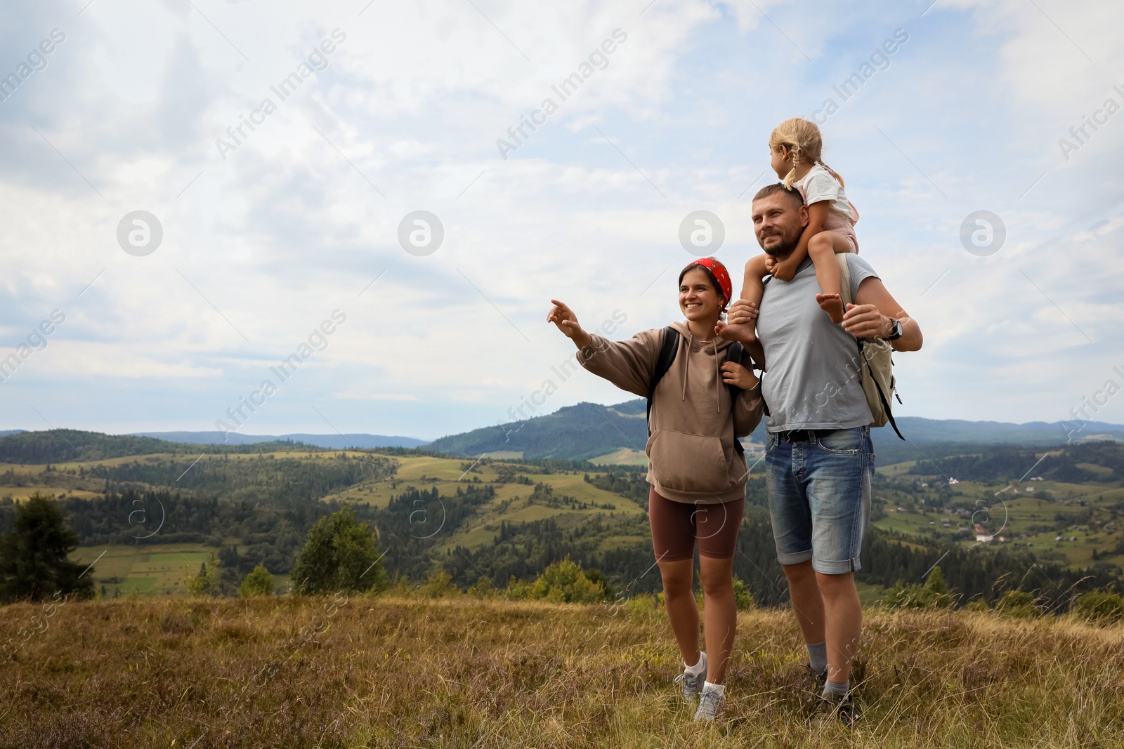 Photo of Happy family with backpacks travelling in mountains, space for text. Active tourism