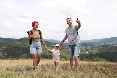 Happy family with backpacks travelling in mountains. Active tourism