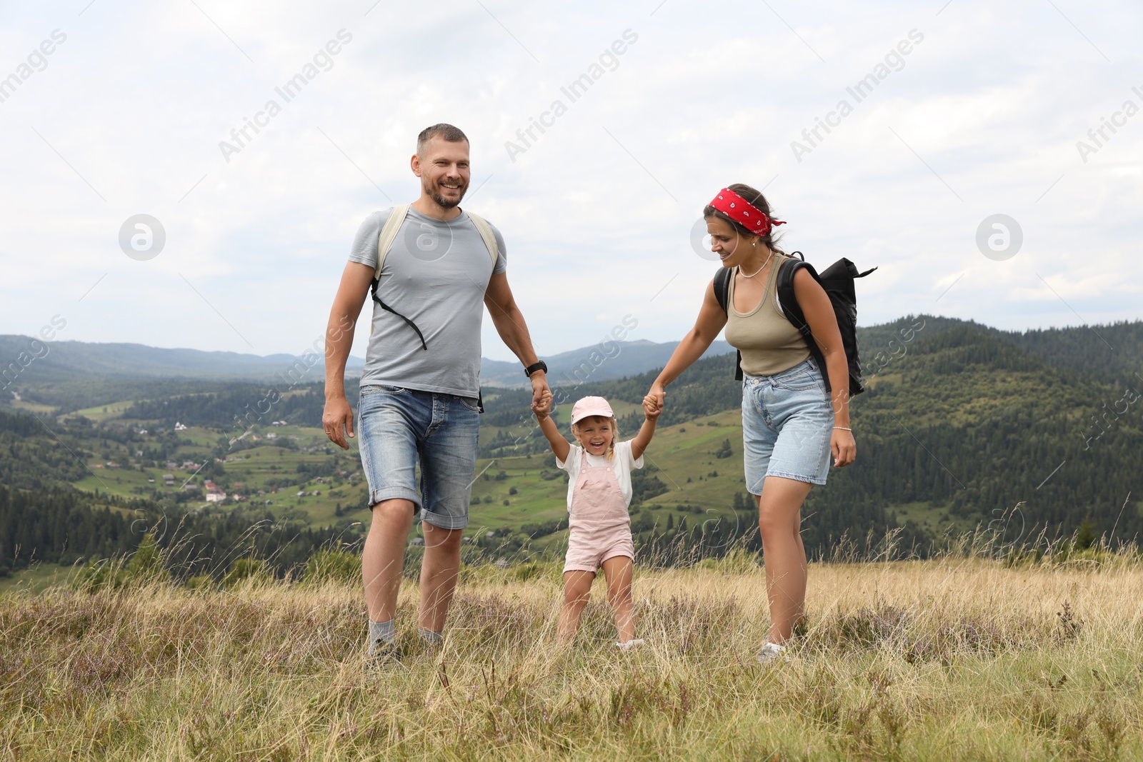 Photo of Happy family with backpacks travelling in mountains. Active tourism