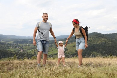 Happy family with backpacks travelling in mountains. Active tourism