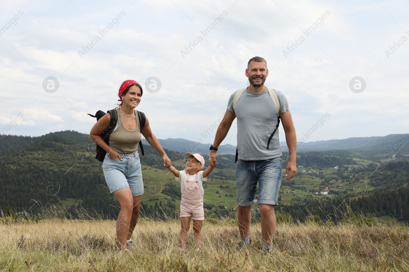 Photo of Happy family with backpacks travelling in mountains. Active tourism