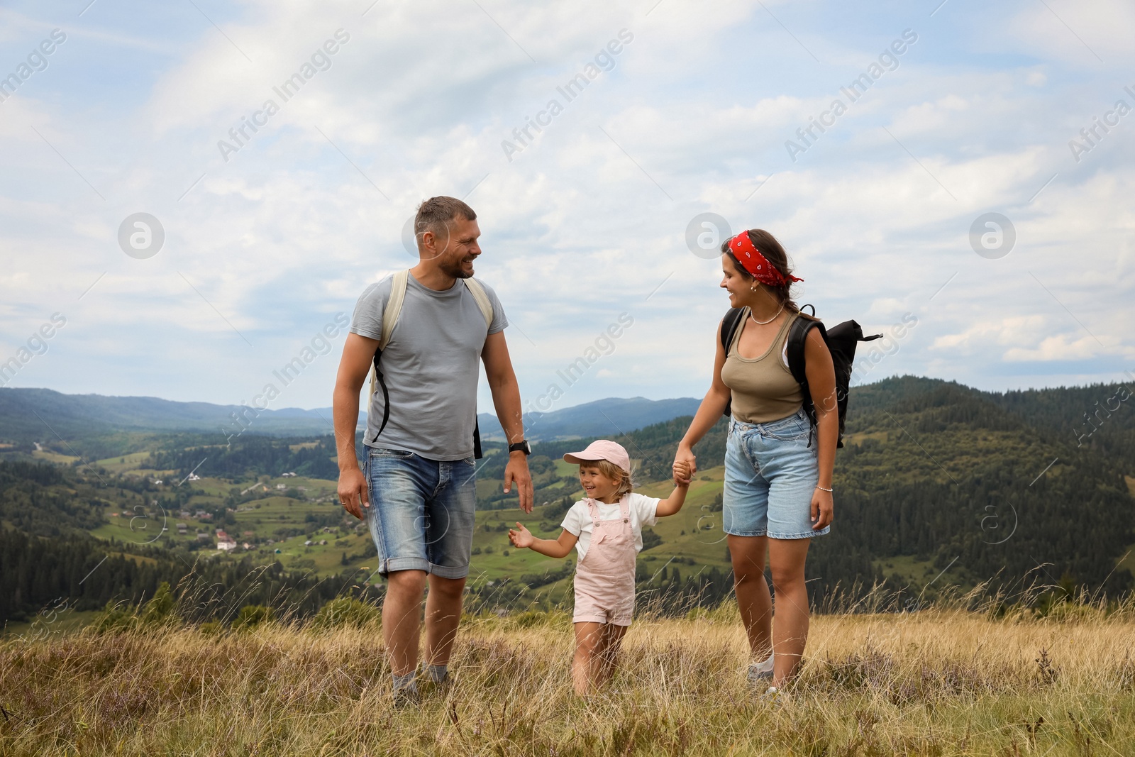 Photo of Happy family with backpacks travelling in mountains. Active tourism