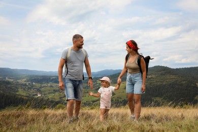 Happy family with backpacks travelling in mountains. Active tourism