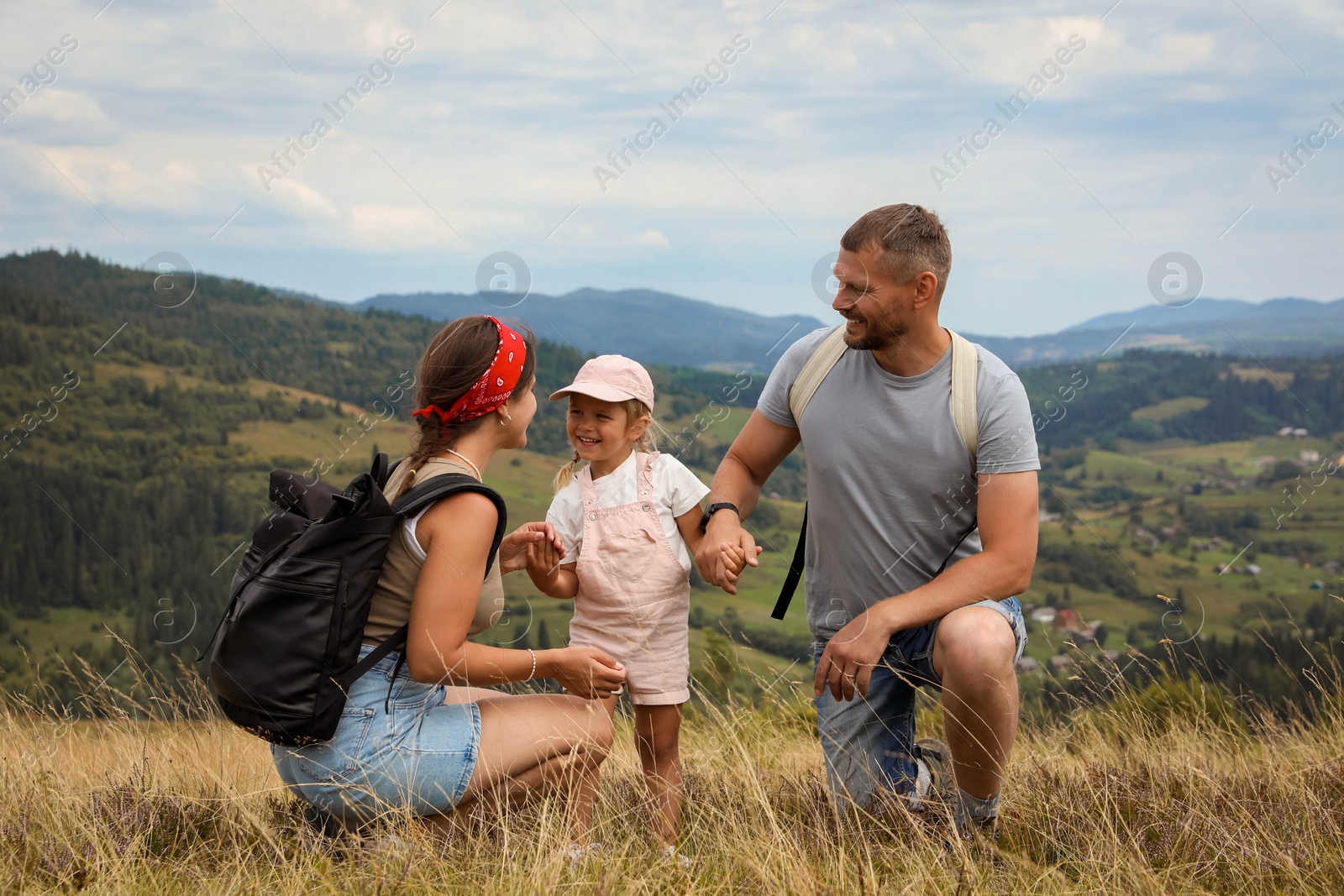 Photo of Happy family with backpacks travelling in mountains. Active tourism