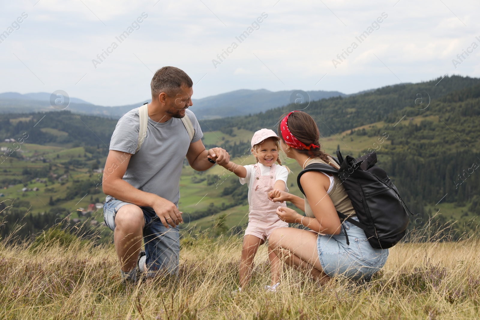 Photo of Happy family with backpacks travelling in mountains. Active tourism