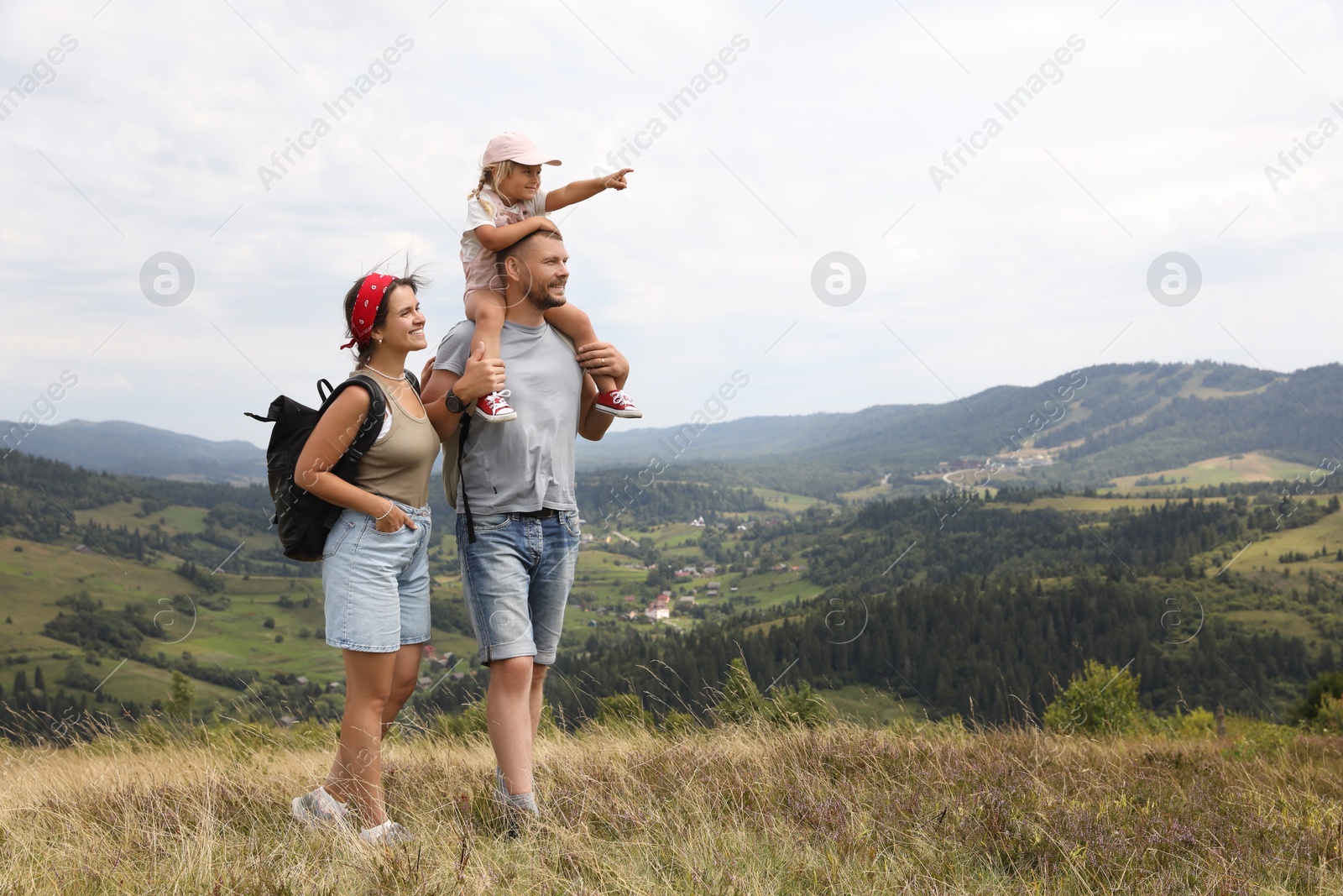 Photo of Happy family with backpacks travelling in mountains, space for text. Active tourism