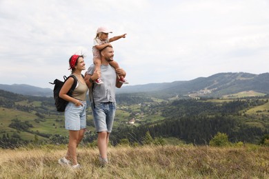 Happy family with backpacks travelling in mountains, space for text. Active tourism