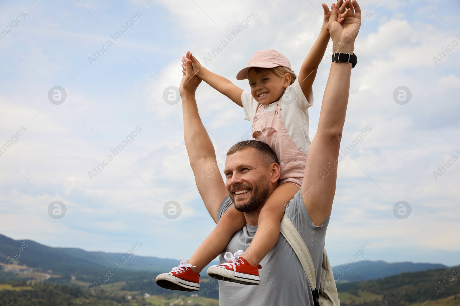 Photo of Happy tourist with his daughter and backpack travelling in mountains. Space for text