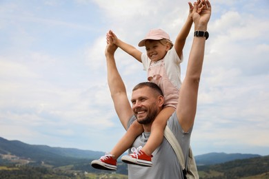 Happy tourist with his daughter and backpack travelling in mountains. Space for text