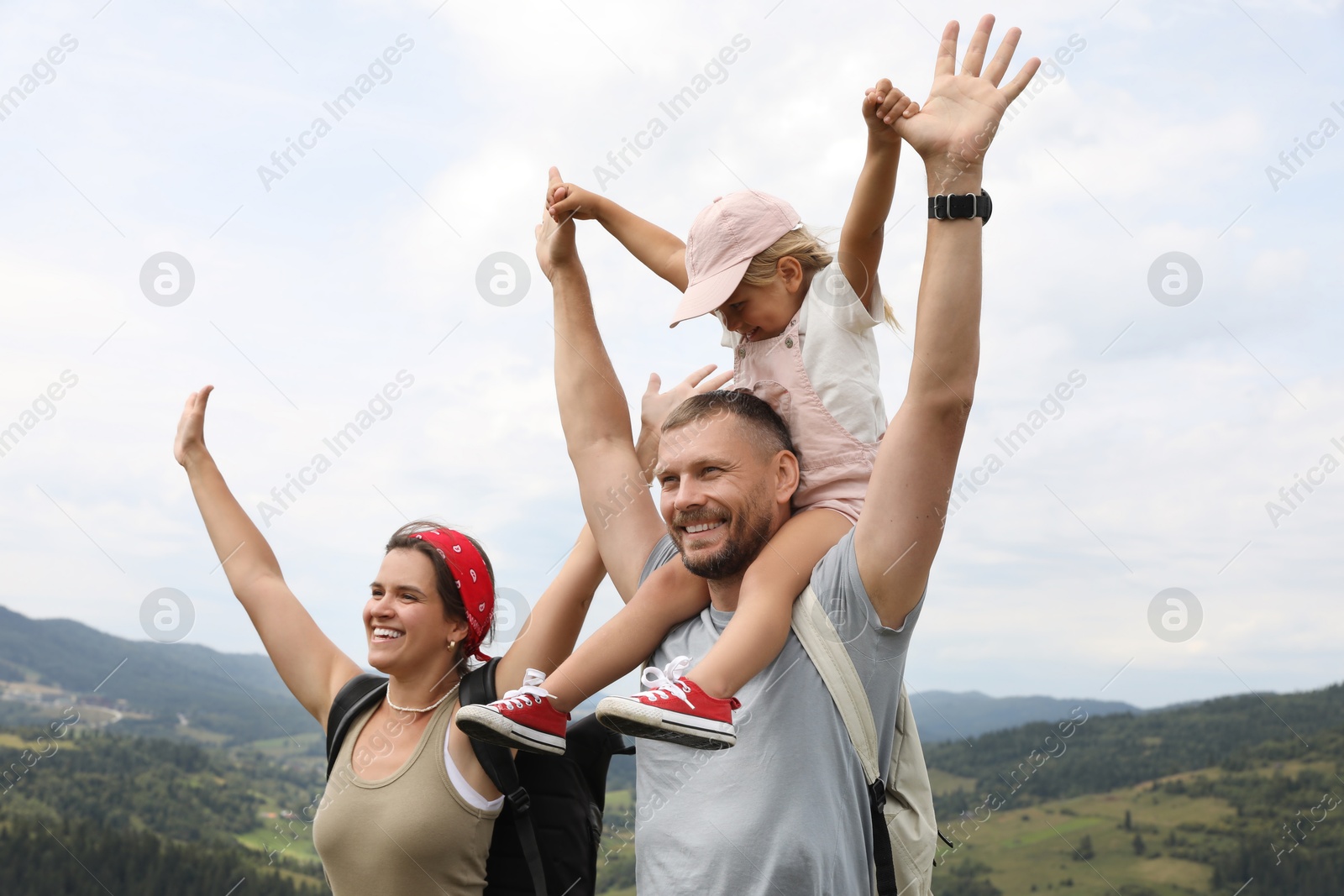 Photo of Happy tourists with backpacks enjoying picturesque landscape with wide open arms