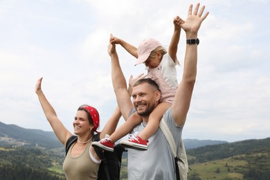 Happy tourists with backpacks enjoying picturesque landscape with wide open arms