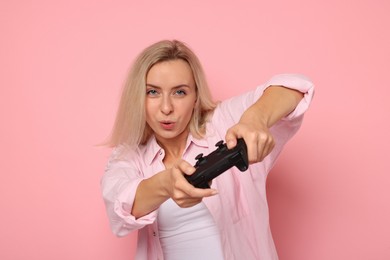 Photo of Woman playing video games with controller on pink background