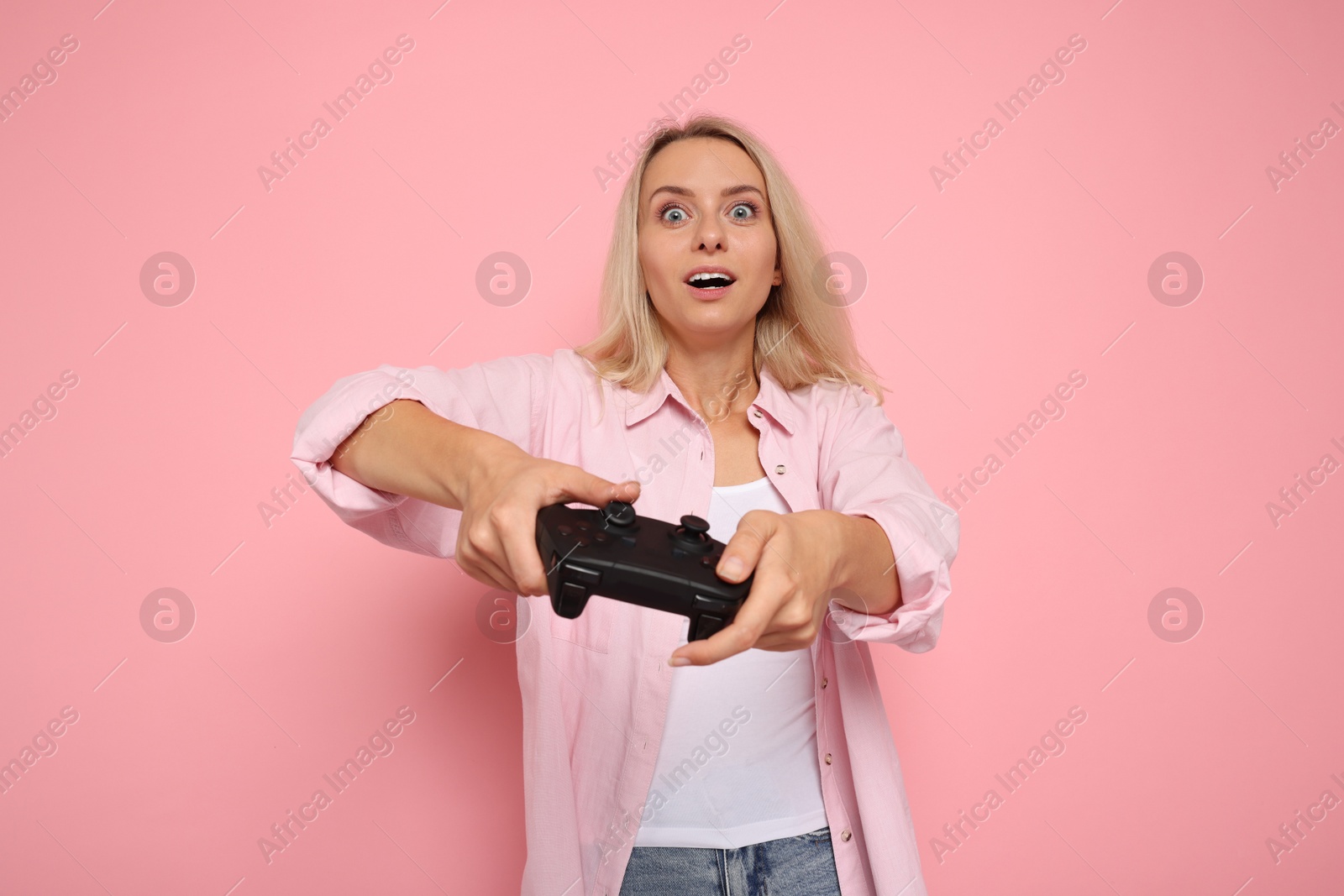 Photo of Excited woman playing video games with controller on pink background