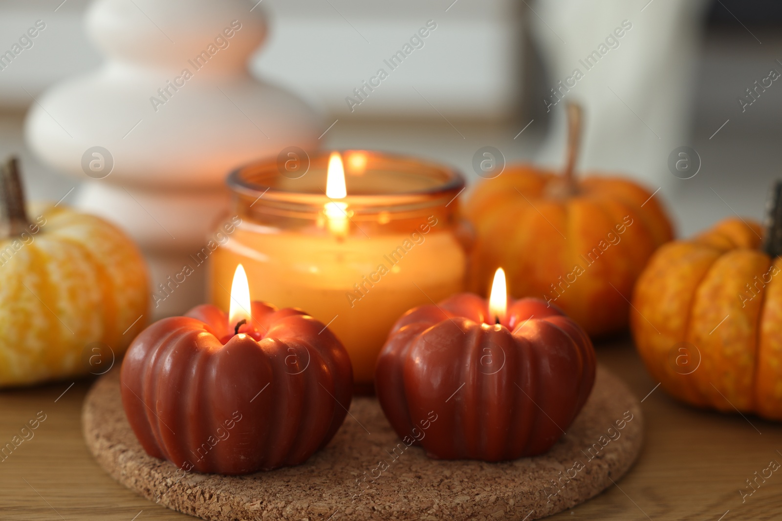 Photo of Burning candles and pumpkins on wooden table, closeup. Autumn atmosphere