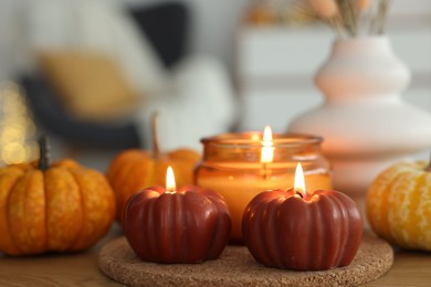 Photo of Burning candles and pumpkins on wooden table, closeup. Autumn atmosphere